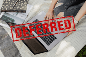 red stamp reading "deferred" over an image of a teenage girl sitting on her bed looking at her laptop